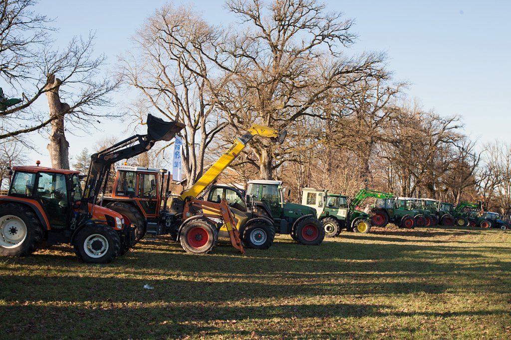 Eine Reihe Traktoren am Rand einer Wiese - im Hintergrund Bäume